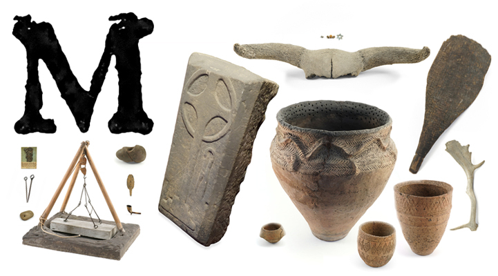 A large printed capital letter M with urns, grave goods, a model mortsafe, a gravestone, a paddle, an antler and an animal skull with large horns.