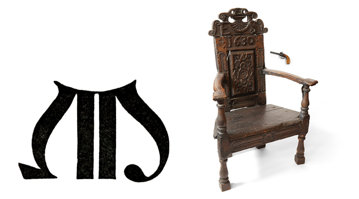 A large printed capital letter M, a wooden chair and a pistol.