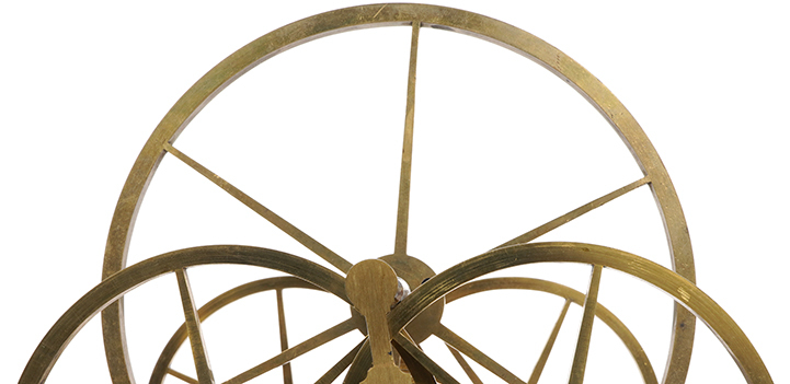 Close up of a large brass wheel on a steel axel resting on four smaller wheels.