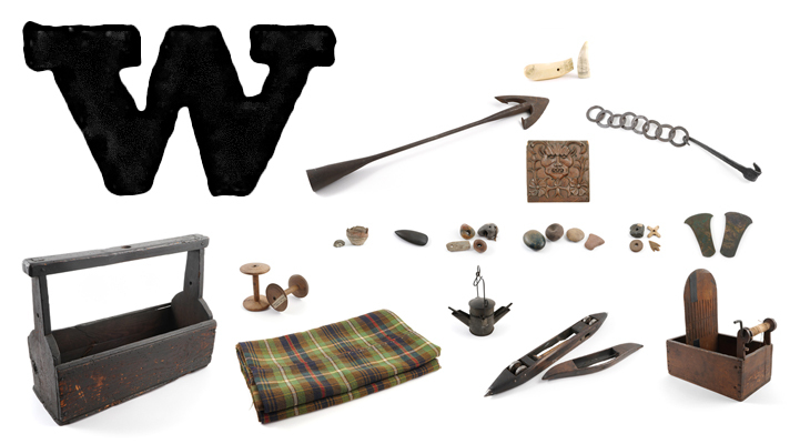 A large printed capital letter W with scrimshaw, a harpoon, small charms, fabric and weaving equipment.