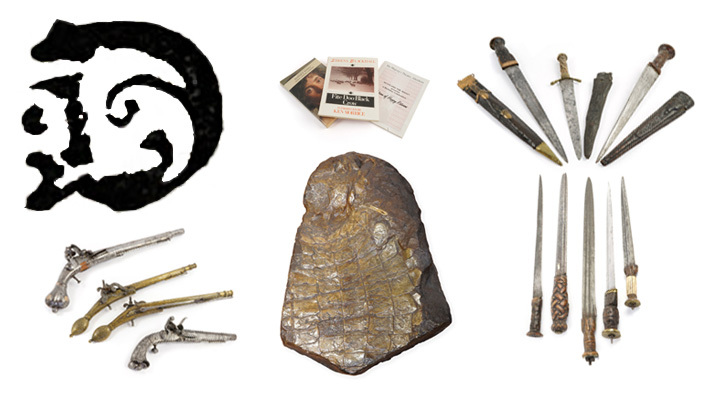 A large ornate printed capital letter D with pistols, short swords, books and a fossil.