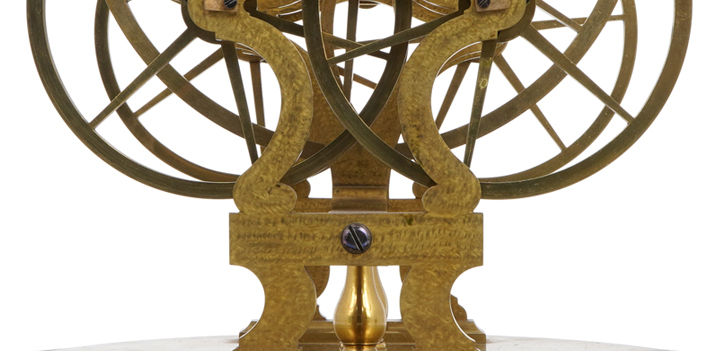 Close up of a mechanism with brass wheels on a stand.