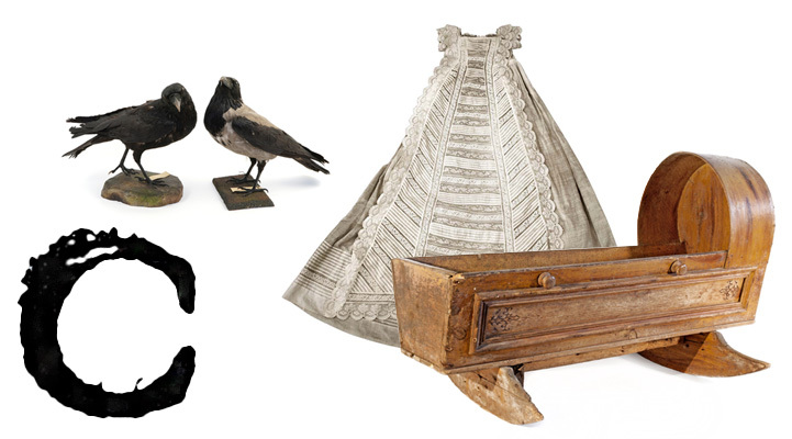 A large printed capital letter C with crows, a christening dress and a cradle.