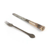 Silver knife and fork. The fork has three tines and its handle ends in a leaf shape, the knife has a mark on the blade consisting of a crown and the letter P, and is inscribed Marischal College Abdn. on the handle.