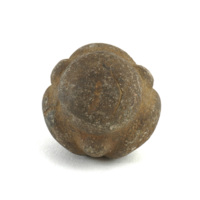 Carved stone ball. Roughly the size of a tennis ball. Brown stone ball with four large, circular knobs and an additional four small round knobs in between the larger ones.