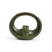 Terret. A bronze, roughly oval shaped ring covered in a dark, smooth green patina. The ring is narrow at the top and thickens toward the bottom which is flat and has a ridge projecting into the middle of the ring.