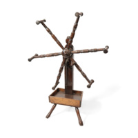 Jack reel. Wooden apparatus about a metre tall, consisting of a tray on three legs and a central column with metal gears. A large knob, from which project six long rods with handles at the end, is at the top of the column connected to the gears.