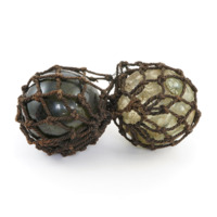 Floats. Two hollow glass balls, one dark green, the other light green. They are wrapped in dark brown netting.