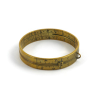 Sundial. A brass ring, bracelet sized, with a small loop. Numbers, lines and letters are engraved on the inner and outer surfaces and a small hole allows light through.