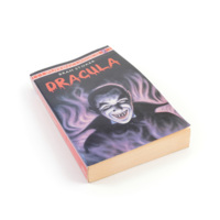 Dracula. A paperback copy of the novel Dracula by Bram Stoker, with an illustration of a vampire surrounded by purple smoke on the cover.