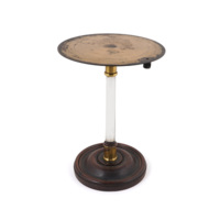 Insulating stand. A thin brass disc about 15 centimetres wide on a glass pillar with a turned wooden base.