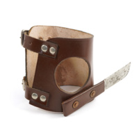 Lousin knife. A brown leather wrist guard which has a small knife attached to it.