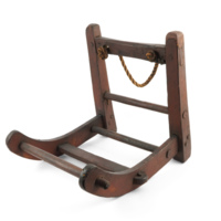 Curracks. A large wooden frame about a foot and a half wide and tall. The frame is L shaped with bars across it. The sides of the horizontal part curve upwards toward the tips, and the bar across the top of the vertical part has a loop of rope attached.