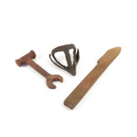 Plough tools. Left to right: a large, rusty spanner shaped tool, an iron muzzle shaped plough sock, and a rusty iron bar with a pointed tip.