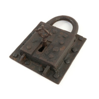 Padlock. A large square padlock, almost a foot wide, with a large key with a circular handle which has a decorative quatrefoil cut out of it. The lock is on a plate with large diamond shaped rivets to affix it to a wall.