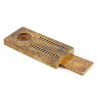 Chinese compass. A small rectangular wooden box with two rows of notches along its length on the top side. There is also a circular cavity with a pin in the centre on which the needle would have been. The cavity and notches have Chinese characters around them. There is a panel of wood with concentric rings and characters on it which slides out from the underside of the box; it has feet allowing it to stand in the notches.