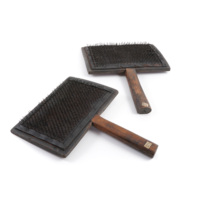 Carding combs. Two large rectangular wooden combs with handles. A large number of small iron pins, bent slightly in the middle, project from the bodies of the combs.