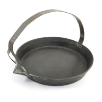 Frying pan. A wide circular iron pan with a spout, and a handle looping over the top.