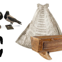 A large printed capital letter C with crows, a christening dress and a cradle.