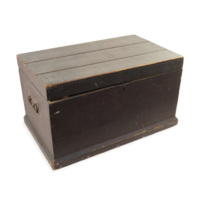 Kist. A large flat topped rectangular wooden chest about two feet wide, with iron handles.