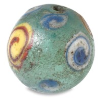 Ball. A bluish green glass ball about the size of a marble, with white and blue, and red and yellow spirals on the surface.