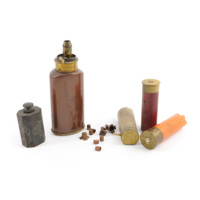 Shotgun paraphernalia. A small steel bottle of gun oil, a polished copper coloured flask with a brass spout containing shot and powder, a handful of tiny copper caps and three shotgun cartridges.