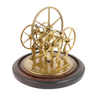 A large brass wheel sitting on four smaller wheels, in a brass frame on a circular wooden stand. The smaller wheels spin at a much slower rate when the large wheel is spun.